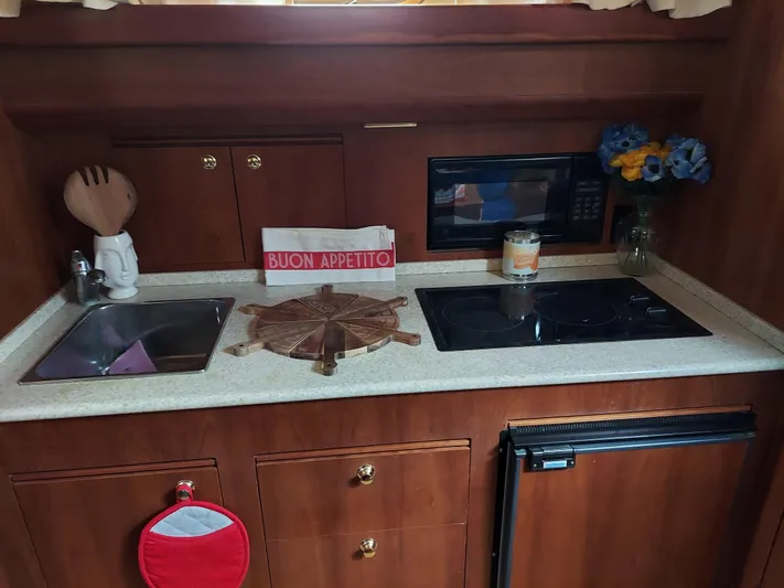 No Name Yacht Photos Pics Kitchen area in a 2001 Apreamare 10M Cabinato boat with sink, stove, and decor.