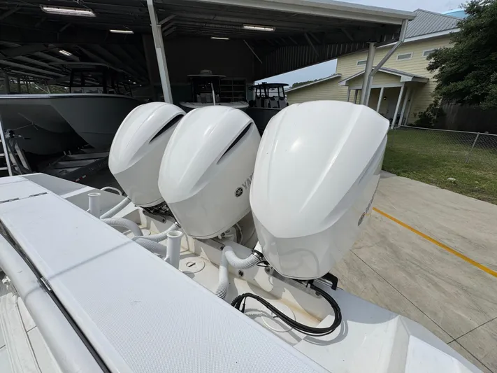  Yacht Photos Pics Triple outboard engines on a 2018 Jupiter 34 HFS boat, parked under a shelter.