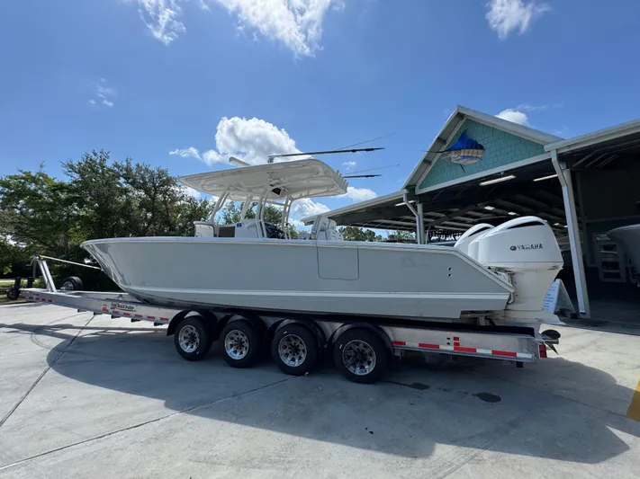  Yacht Photos Pics 2018 Jupiter 34 HFS boat on trailer, parked outside a building under a clear sky.