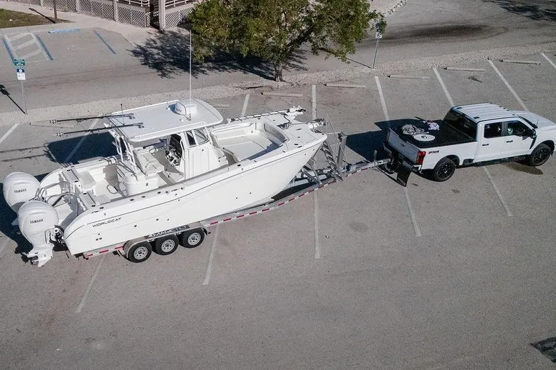  Yacht Photos Pics 2024 World Cat 295 CC boat on trailer, towed by a white truck in parking lot.
