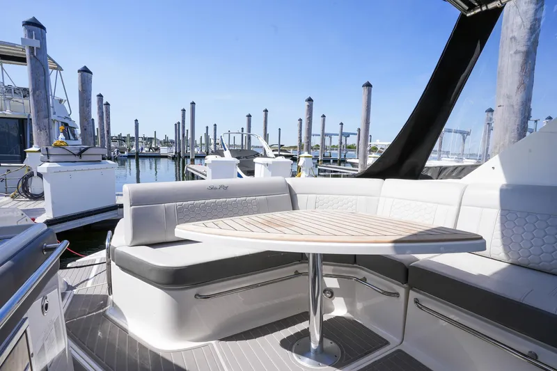  Yacht Photos Pics 2023 Sea Ray Sundancer 320 yacht with elegant seating and table in a marina setting.