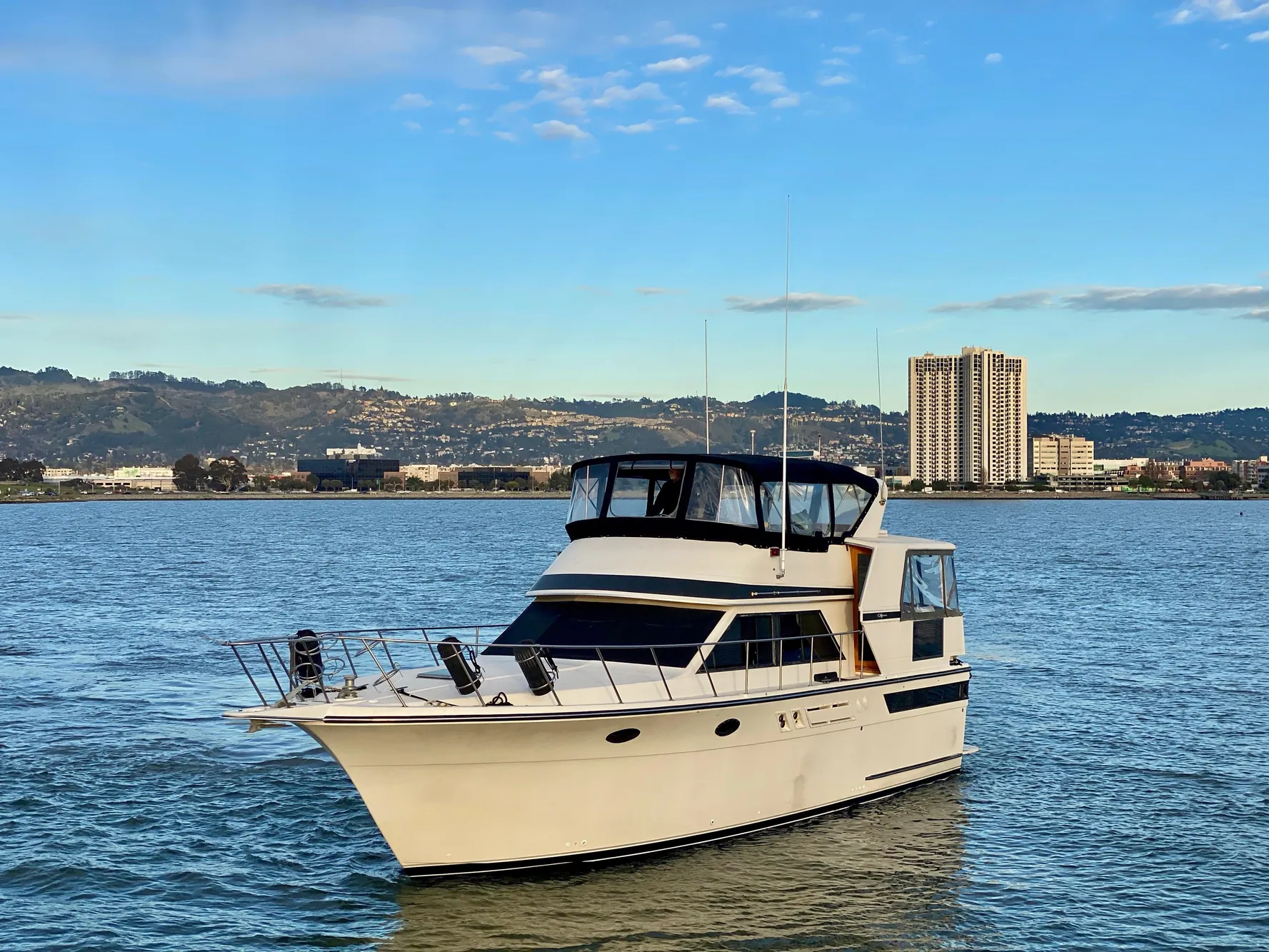 1988 Californian Sundeck Motoryacht on scenic water with city skyline backdrop.