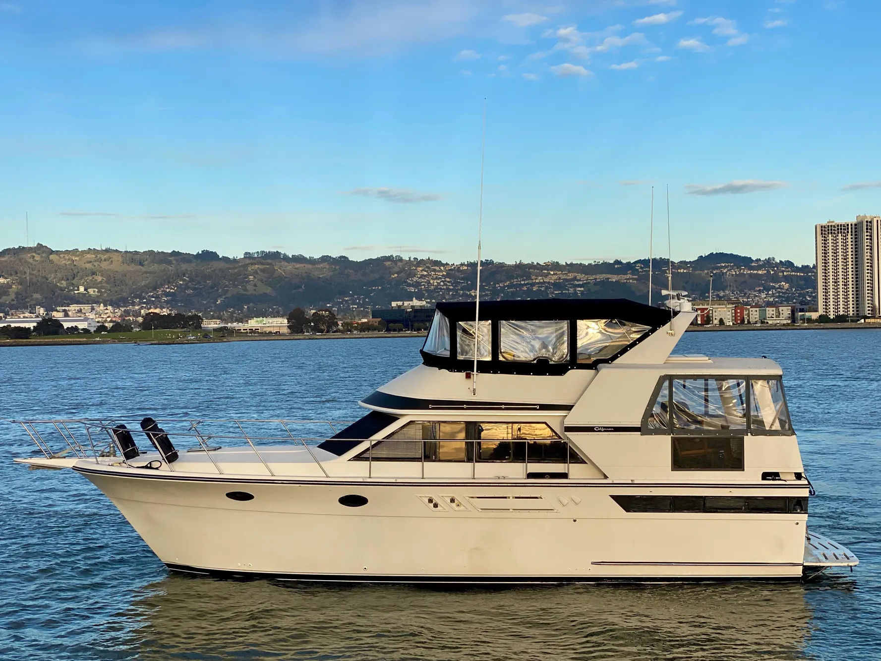 1988 Californian Sundeck Motoryacht on calm water with cityscape background.