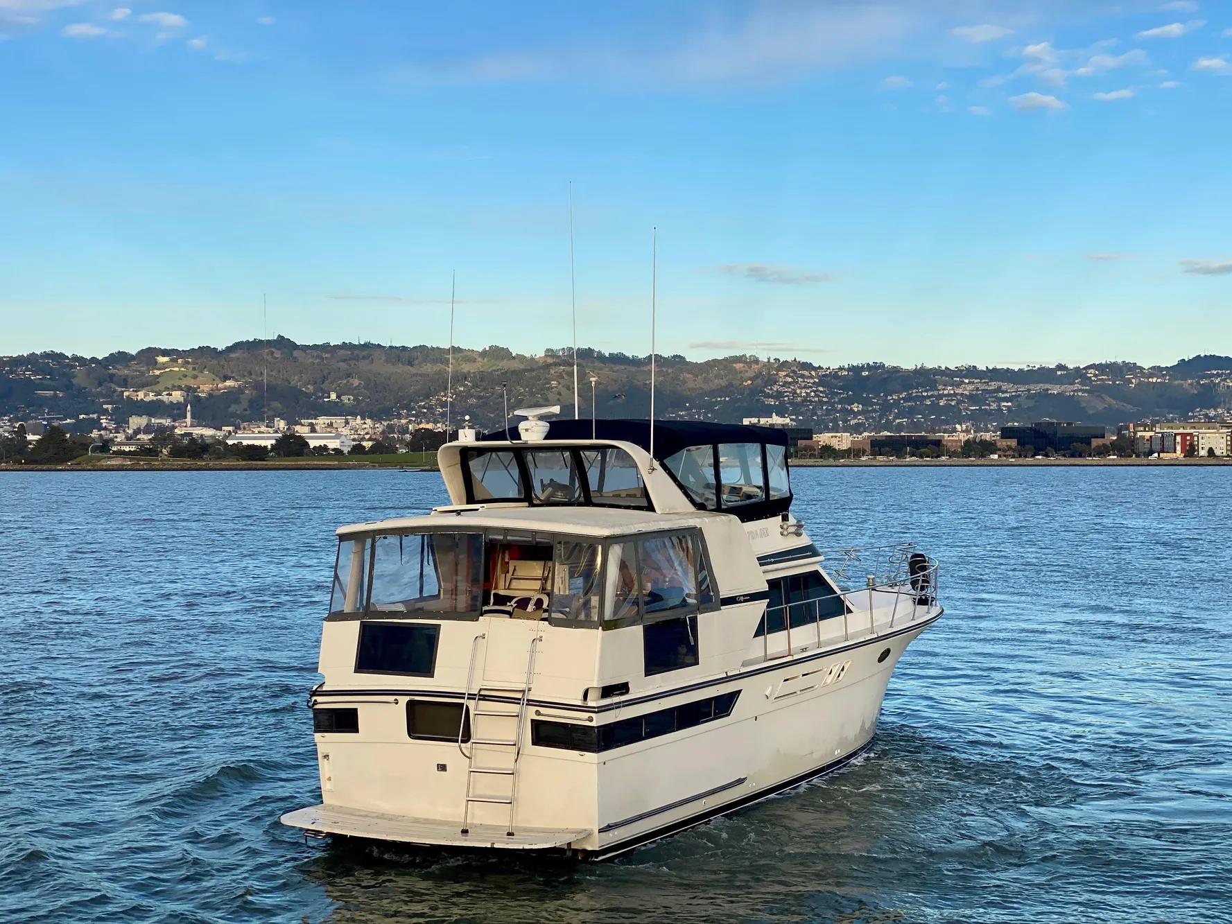 1988 Californian Sundeck Motoryacht cruising on a scenic lake with hills in the background.