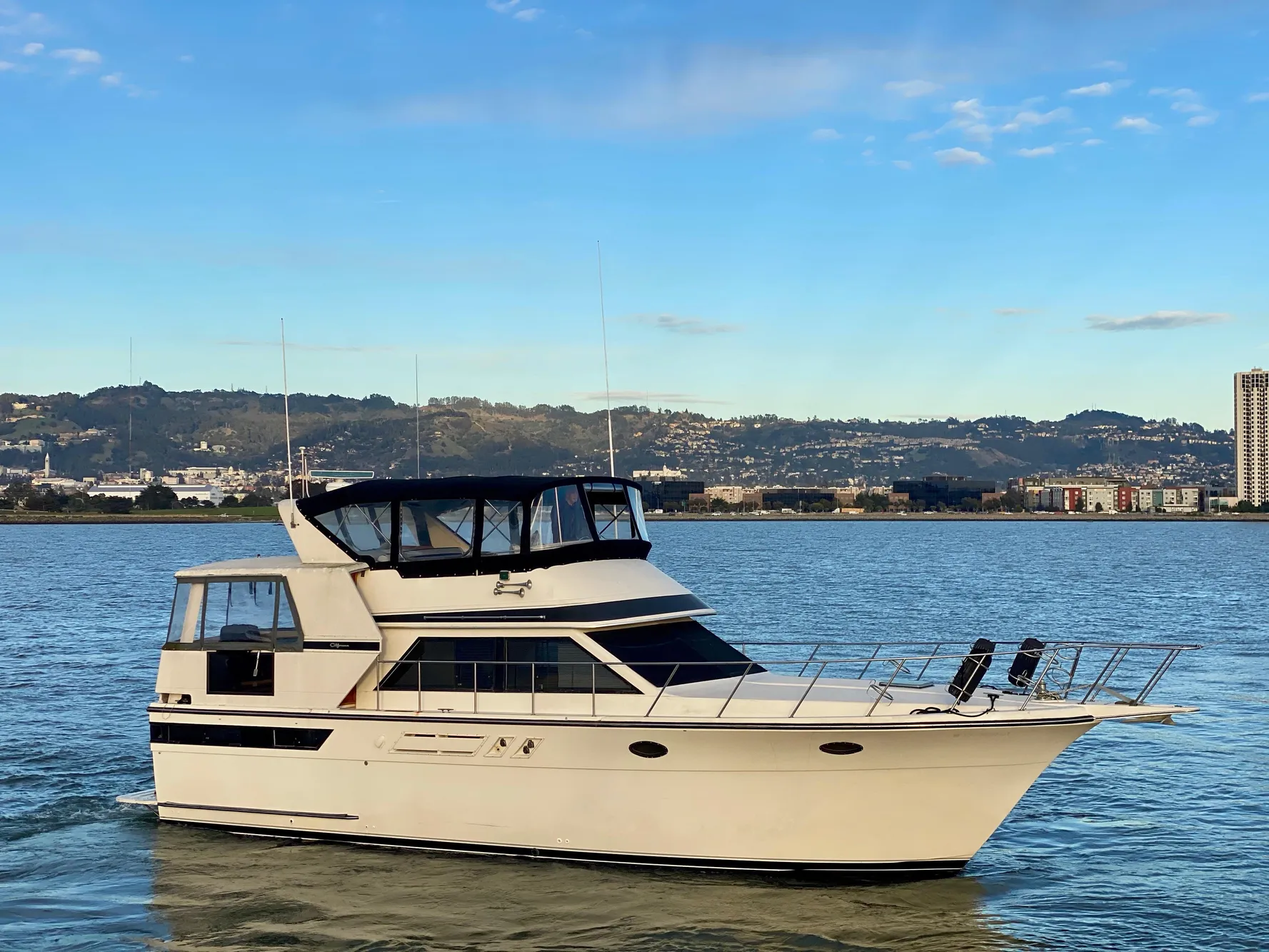 1988 Californian Sundeck Motoryacht cruising on a calm lake with scenic hills in the background.