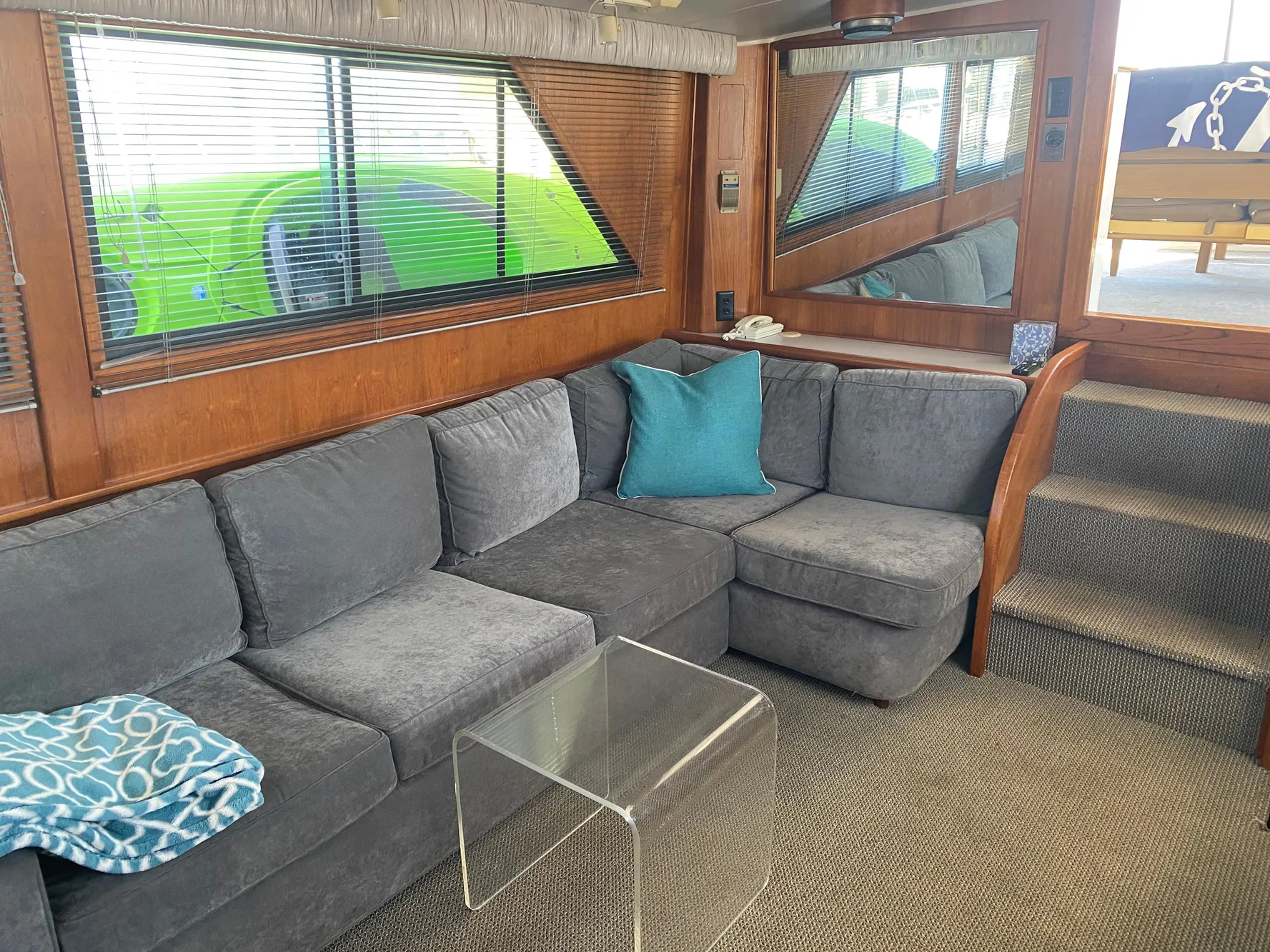 Interior of 1988 Californian Sundeck Motoryacht with gray sofa and glass table.