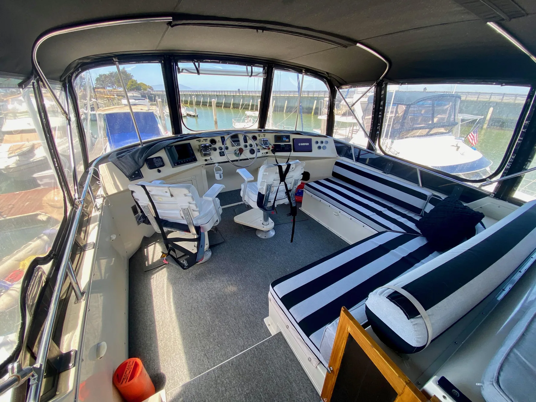 1988 Californian Sundeck Motoryacht interior with striped seating and helm, docked at marina.