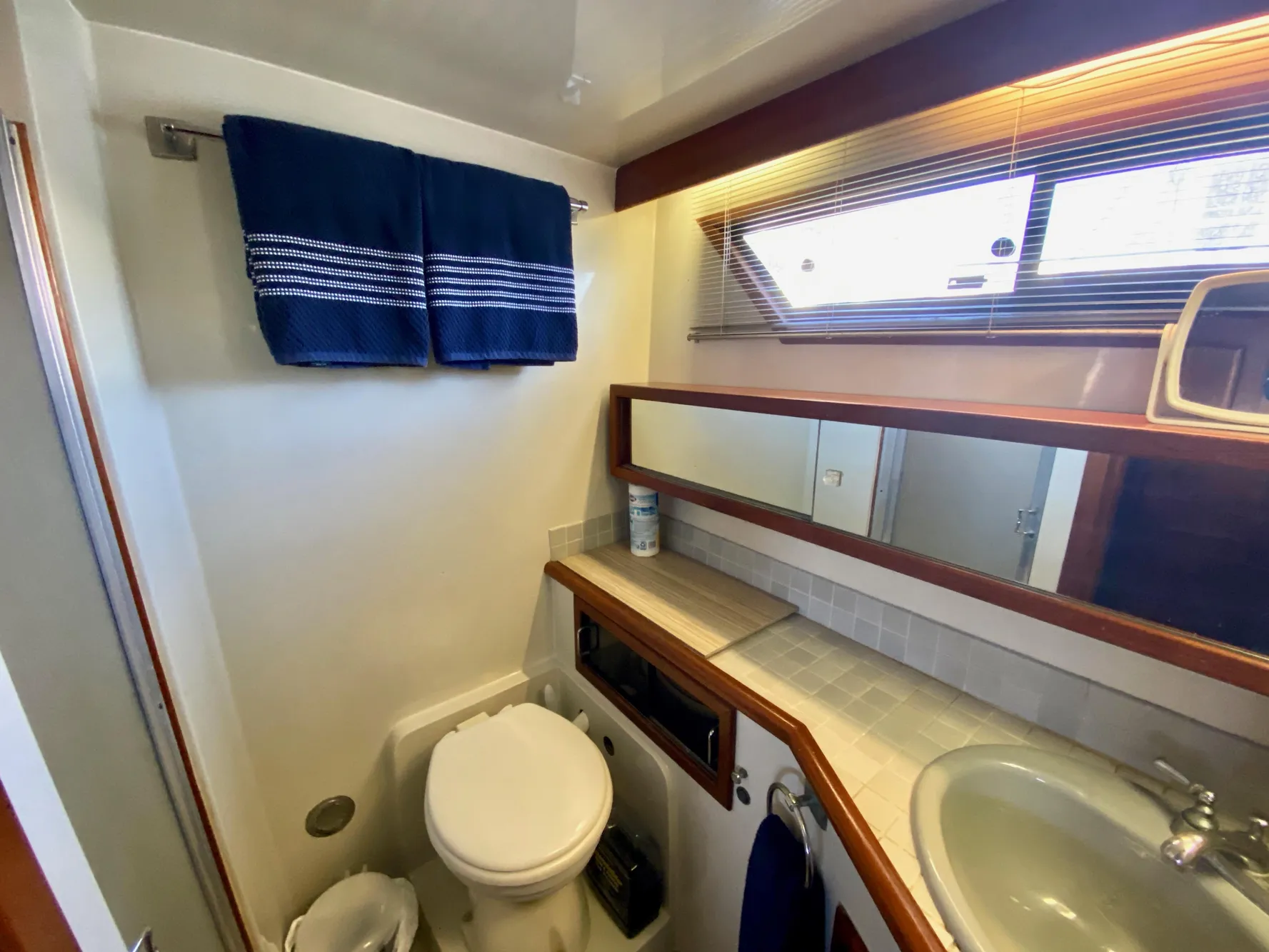 Bathroom interior of 1988 Californian Sundeck Motoryacht with sink, toilet, and window.