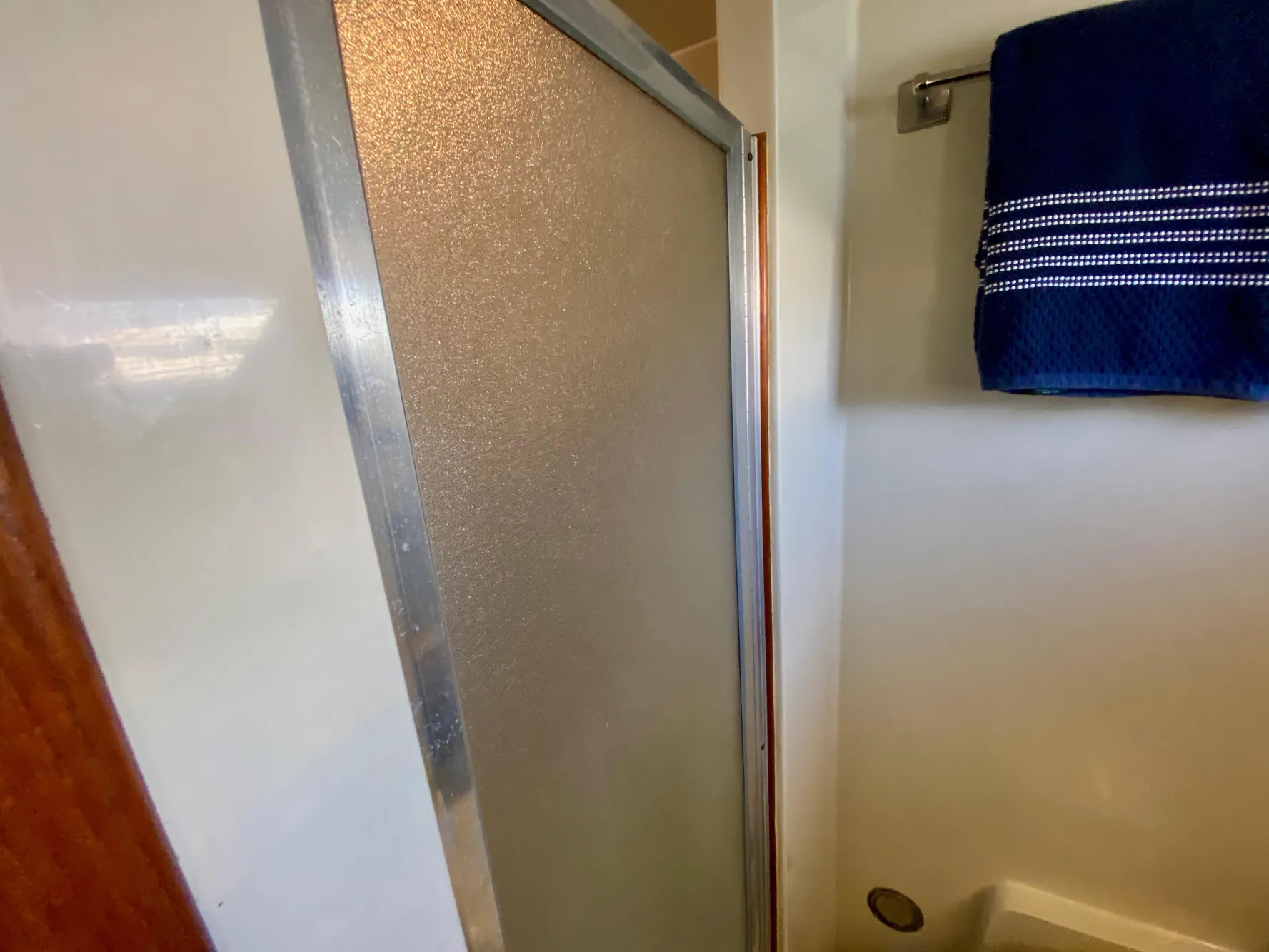 Shower area in 1988 Californian Sundeck Motoryacht with blue towel and frosted glass door.