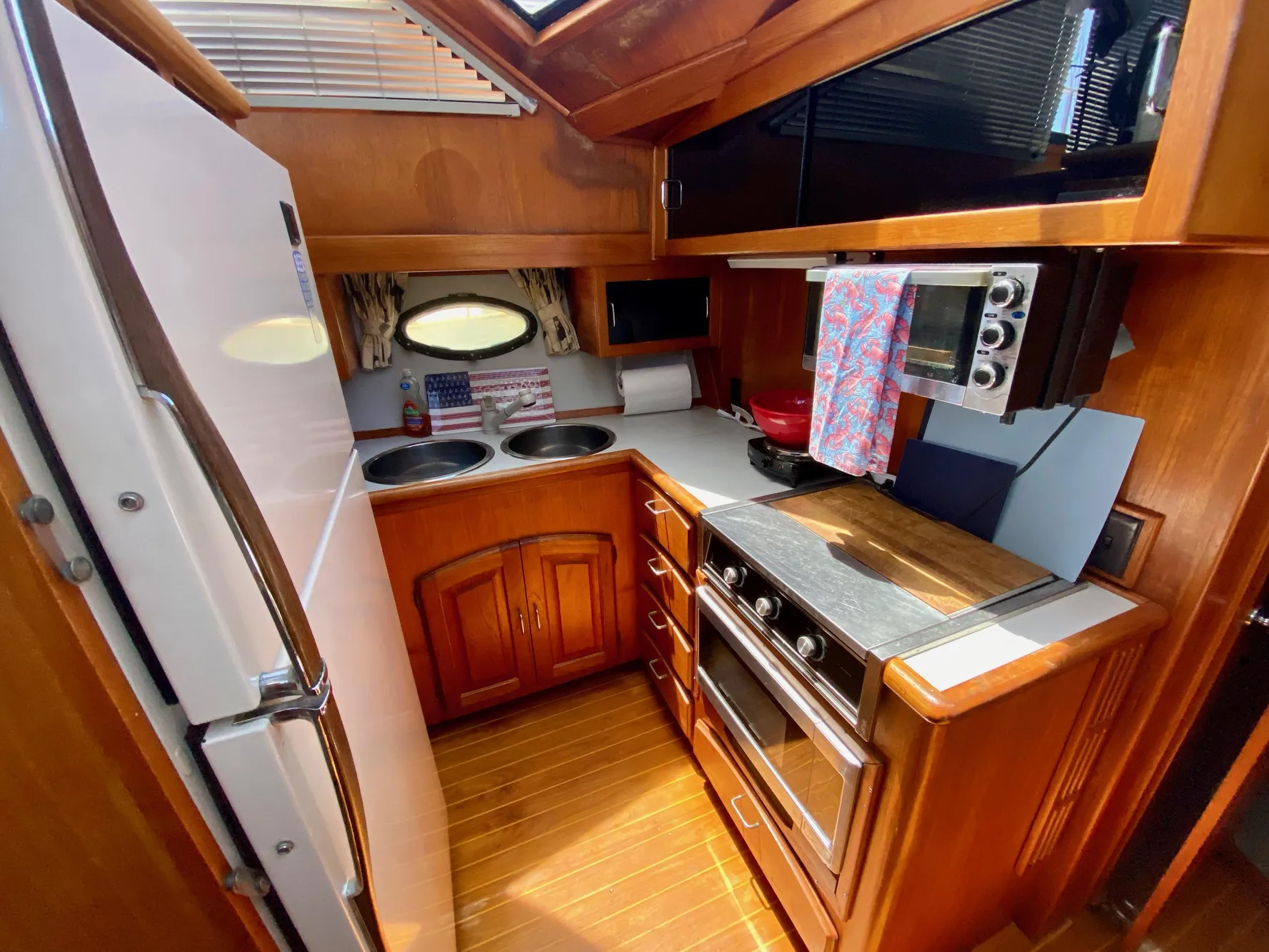 1988 Californian Sundeck Motoryacht kitchen with wood cabinetry, stove, microwave, and refrigerator.