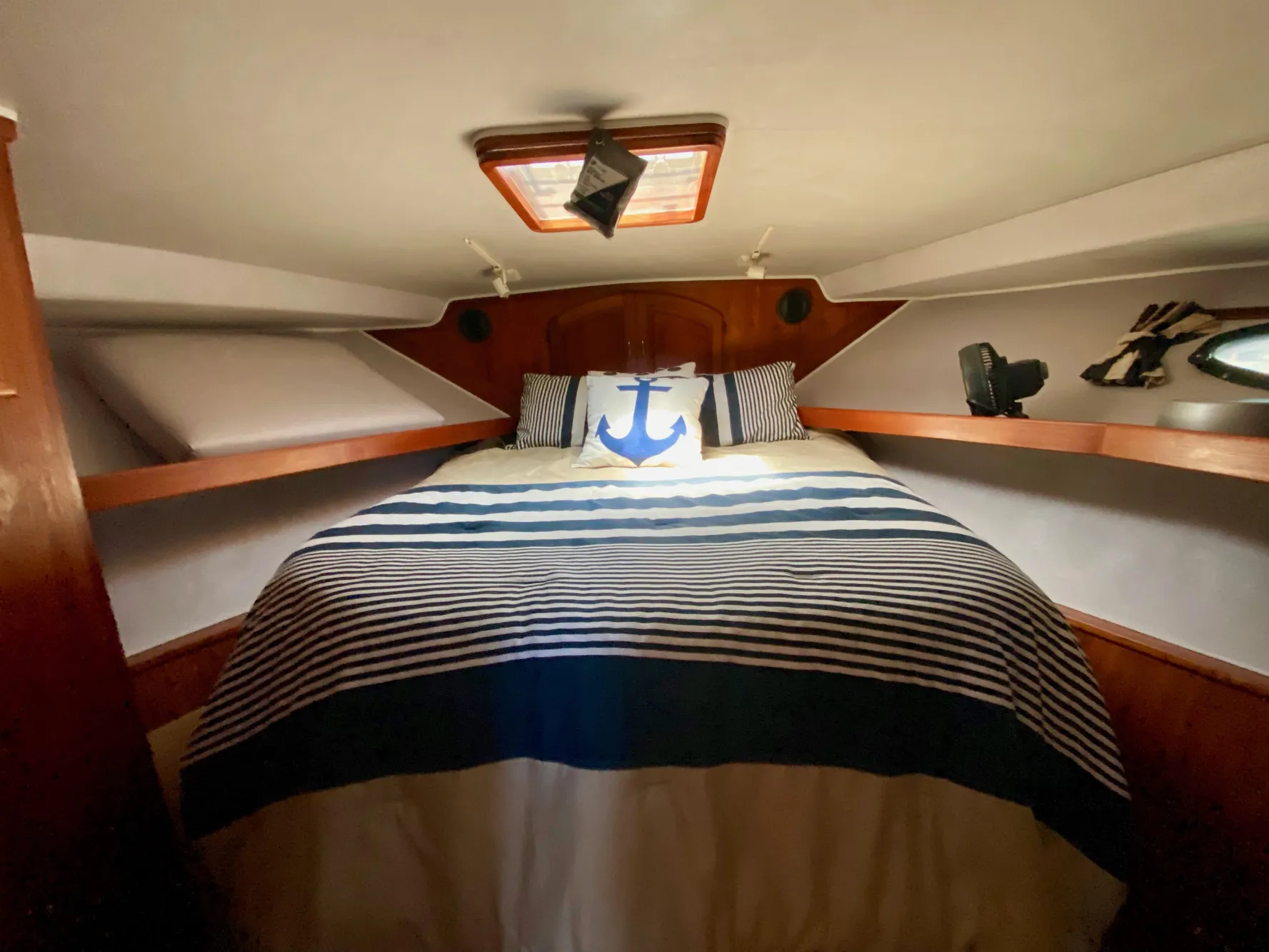 Cozy bedroom in 1988 Californian Sundeck Motoryacht with nautical-themed bedding.