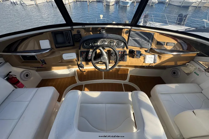 Coral Dreams Yacht Photos Pics 2003 Carver 444 Cockpit Motor Yacht helm with steering wheel, controls, and seating, overlooking marina.