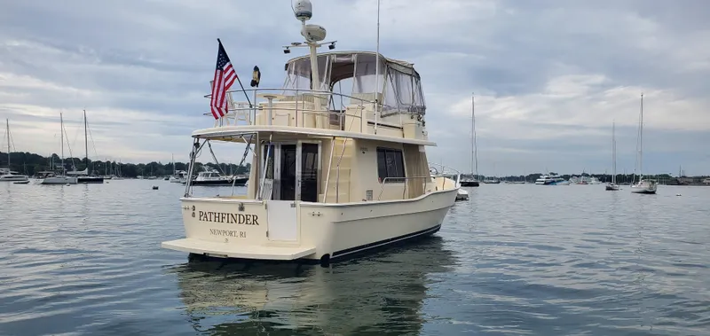 Pathfinder Yacht Photos Pics 2004 Mainship 400 Trawler, anchored in a scenic harbor with other boats.