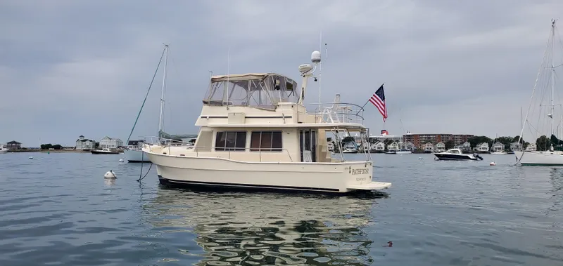 Pathfinder Yacht Photos Pics 2004 Mainship 400 Trawler on calm water, with American flag, overcast sky.