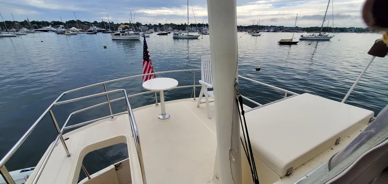 Pathfinder Yacht Photos Pics 2004 Mainship 400 Trawler deck with table, chair, and American flag, overlooking a marina.