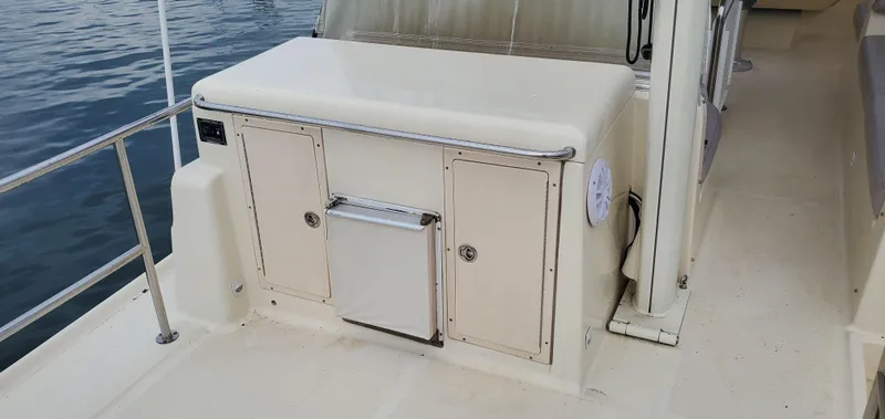 Pathfinder Yacht Photos Pics 2004 Mainship 400 Trawler deck with storage compartments and railing, docked on calm water.