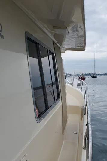 Pathfinder Yacht Photos Pics 2004 Mainship 400 Trawler side view on calm water, showcasing windows and railing.