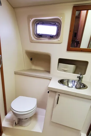 Pathfinder Yacht Photos Pics 2004 Mainship 400 Trawler bathroom with sink, toilet, and porthole window.