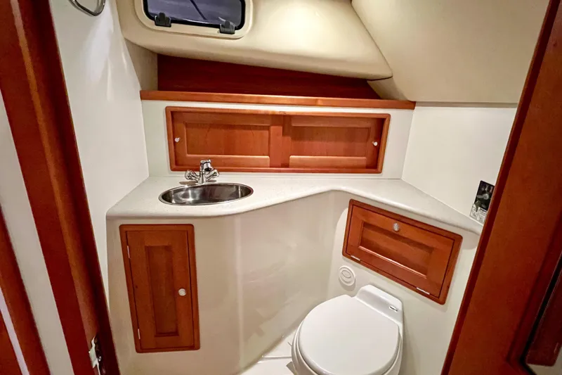  Yacht Photos Pics 2009 MJM 34z Downeast yacht bathroom with sink, toilet, and wooden cabinetry.