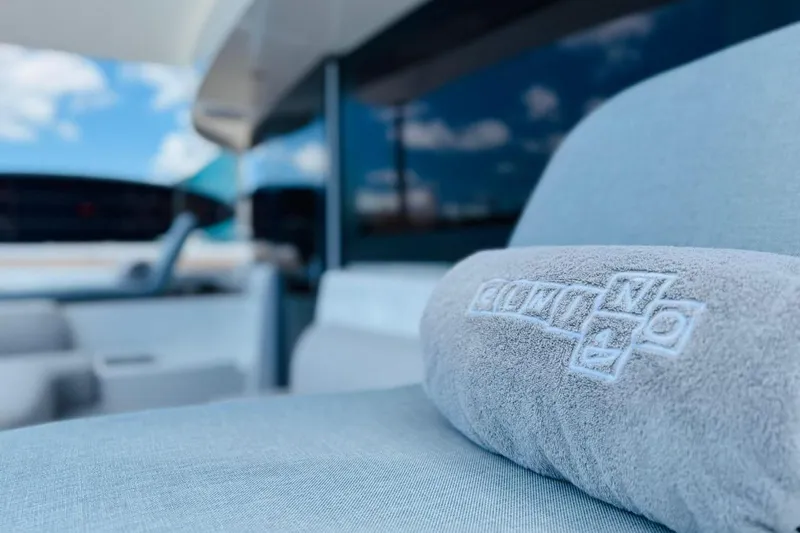 El Nino Yacht Photos Pics Luxurious seating on 2024 Lagoon 65 yacht with embroidered cushion, blue sky background.