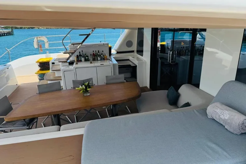 El Nino Yacht Photos Pics Luxurious 2024 Lagoon 65 yacht deck with dining area and bar, overlooking serene waters.