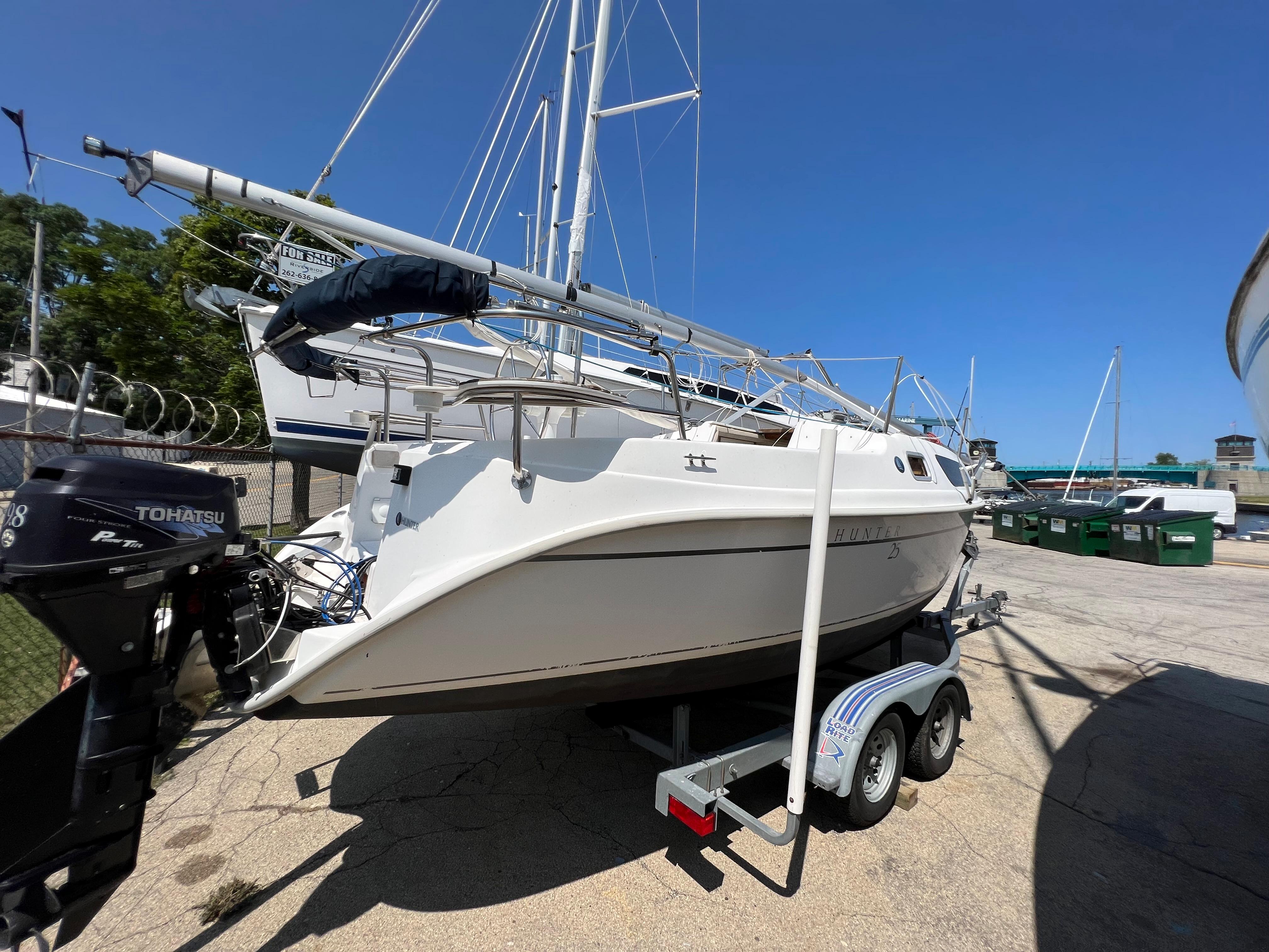 2007 Hunter 25 sailboat on trailer, docked with other boats under clear blue sky.