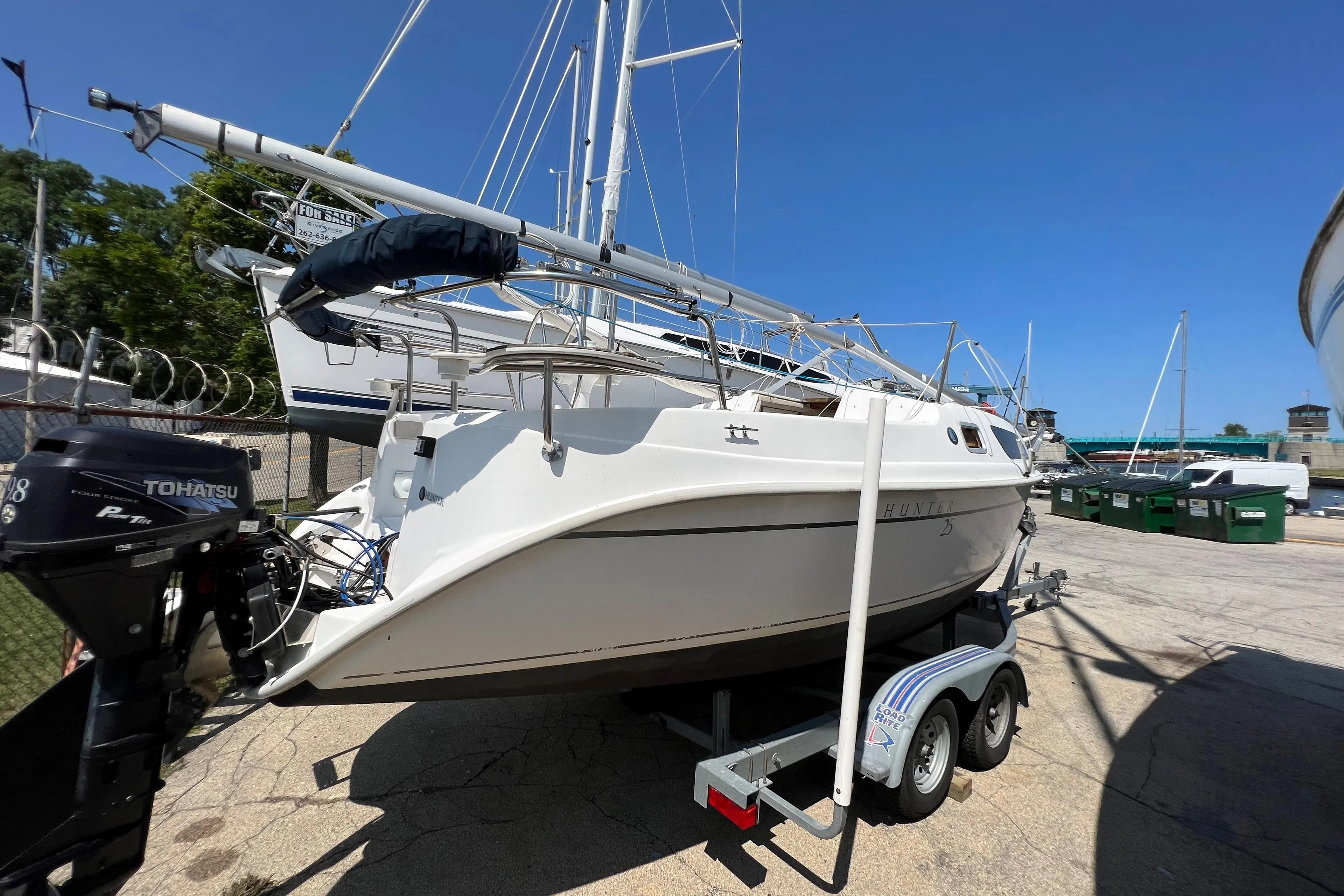 2007 Hunter 25 sailboat on trailer, docked with other boats under clear blue sky.