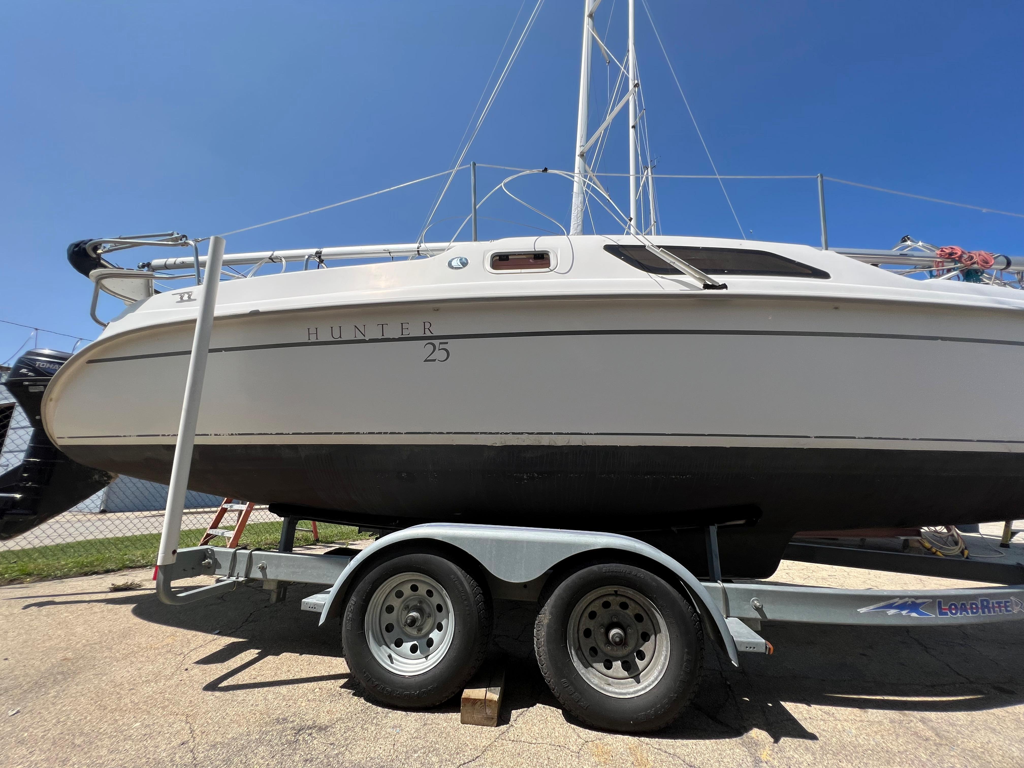 2007 Hunter 25 sailboat on trailer under clear blue sky.