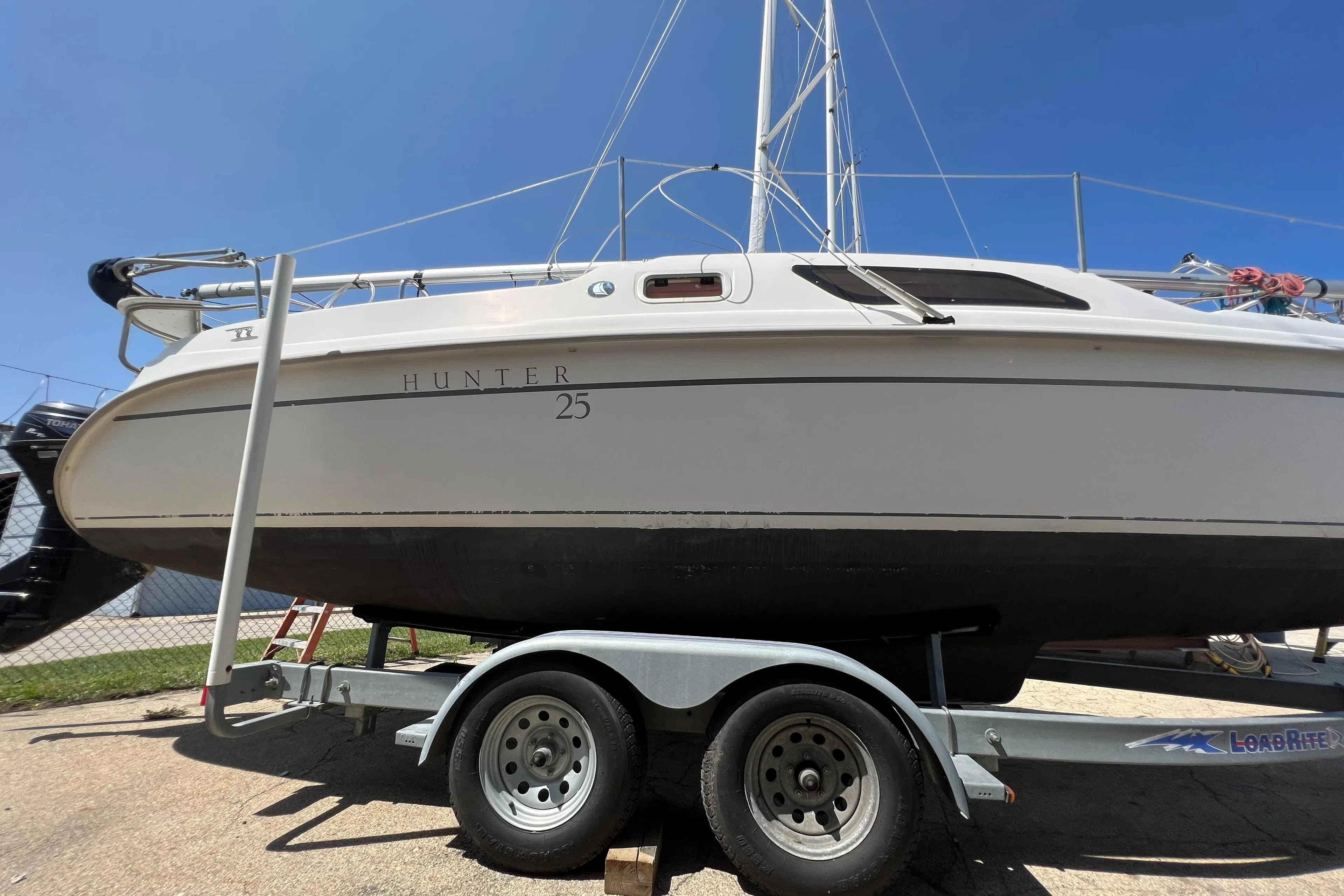2007 Hunter 25 sailboat on trailer under clear blue sky.