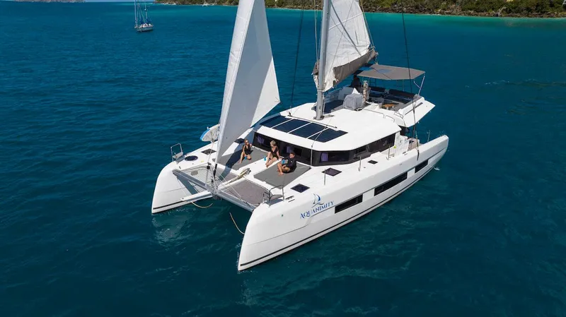  Yacht Photos Pics 2021 Dufour Catamarans 48 sailing on clear blue water, featuring spacious deck and sails.