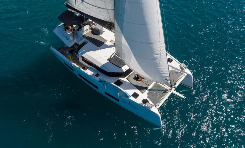  Yacht Photos Pics 2021 Dufour Catamarans 48 sailing on clear blue water, aerial view.