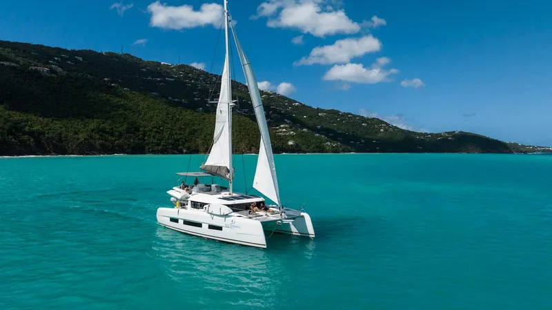  Yacht Photos Pics Sailing Dufour Catamarans 48, 2021 model, on turquoise waters with lush green hills.