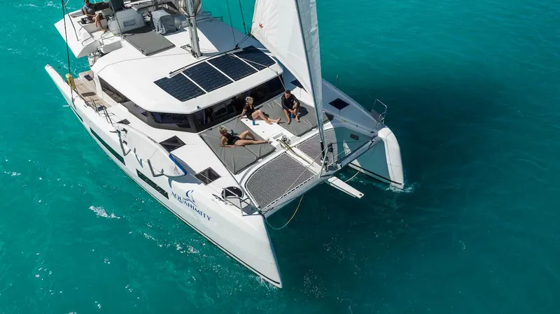  Yacht Photos Pics Dufour Catamarans 48 sailing on turquoise waters, 2021 model, with people relaxing on deck.