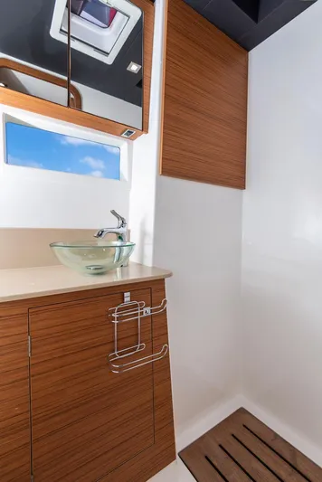  Yacht Photos Pics Modern bathroom interior on 2021 Dufour Catamarans 48, featuring wood cabinetry and glass sink.