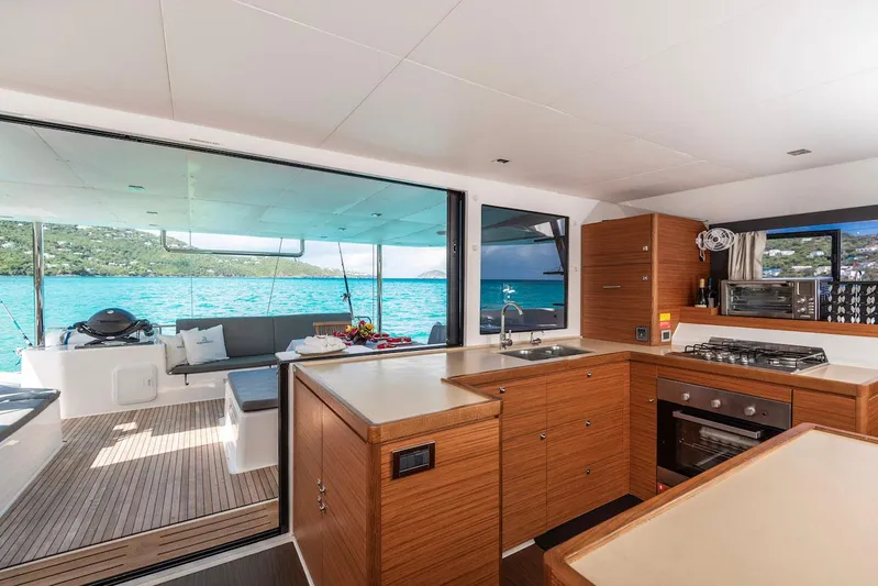  Yacht Photos Pics Modern kitchen and deck view on 2021 Dufour Catamarans 48, overlooking turquoise waters.
