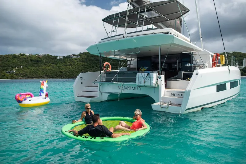 Yacht Photos Pics 2021 Dufour Catamarans 48 anchored with people relaxing on inflatables in turquoise water.