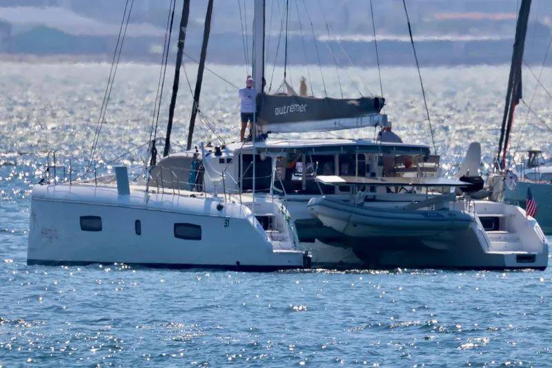 Alegria Yacht Photos Pics 2017 Outremer 51 catamaran sailing on a sunny day with a dinghy attached.