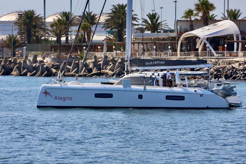 Alegria Yacht Photos Pics 2017 Outremer 51 catamaran "Alegria" docked near palm trees and waterfront buildings.