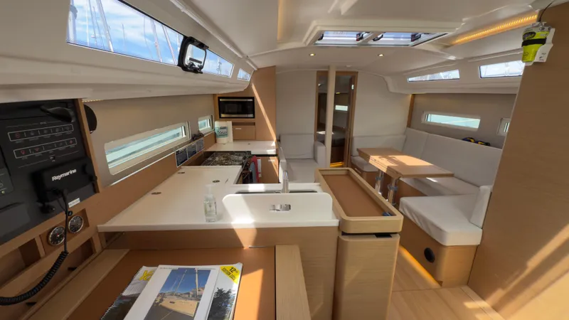  Yacht Photos Pics Modern interior of 2022 Jeanneau Sun Odyssey 410 sailboat, featuring kitchen and seating area.