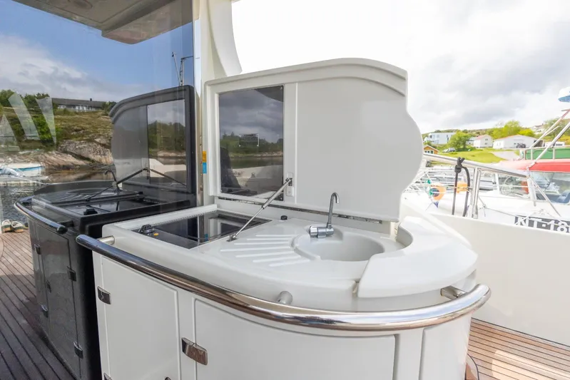  Yacht Photos Pics Outdoor kitchen on 2008 Azimut 62S yacht with sink and grill, docked by scenic shoreline.