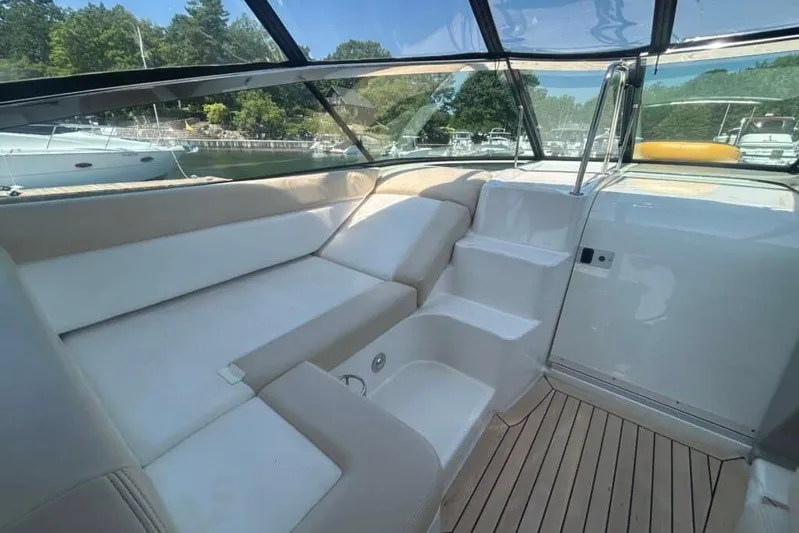  Yacht Photos Pics 2013 Searay 370 Venture boat interior with white seating and steps, docked near greenery.