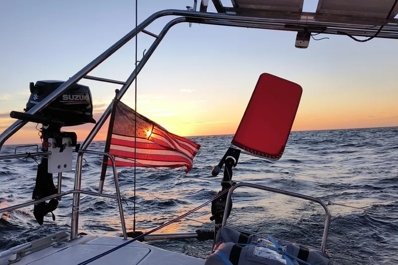 Luthien Yacht Photos Pics Jeanneau Sun Odyssey 42 sailboat at sunset, featuring American flag and ocean view.