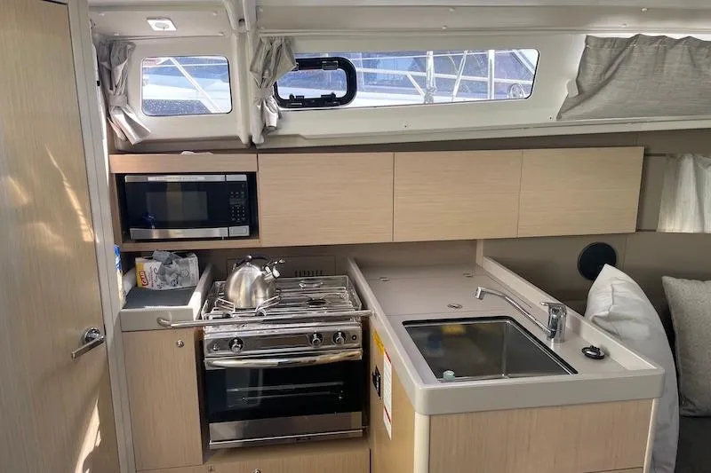 Dulce Vida Yacht Photos Pics Interior of 2022 Beneteau Oceanis 35.1 yacht kitchen with stove, sink, and microwave.