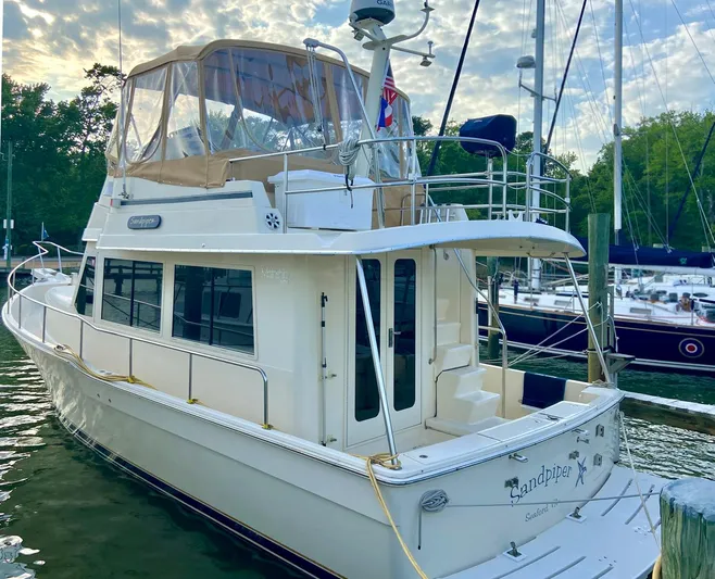 Sandpiper Yacht Photos Pics 2004 Mainship 340 yacht docked at marina, featuring upper deck and enclosed cabin.