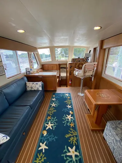 Sandpiper Yacht Photos Pics Interior of 2004 Mainship 340 yacht with blue sofa, nautical rug, and wooden helm.