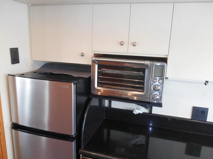 Suspense Yacht Photos Pics Compact kitchen area in a 2005 Inace Trawler with stainless steel appliances.