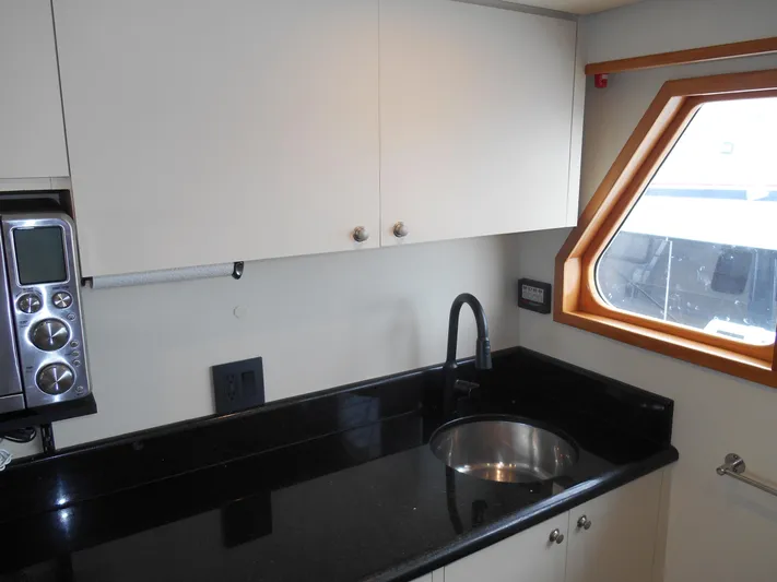 Suspense Yacht Photos Pics Compact kitchen area in a 2005 Inace Trawler with black countertop and stainless steel sink.