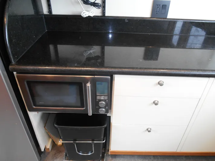 Suspense Yacht Photos Pics Kitchen area on 2005 Inace Trawler with microwave, black countertop, and white cabinets.