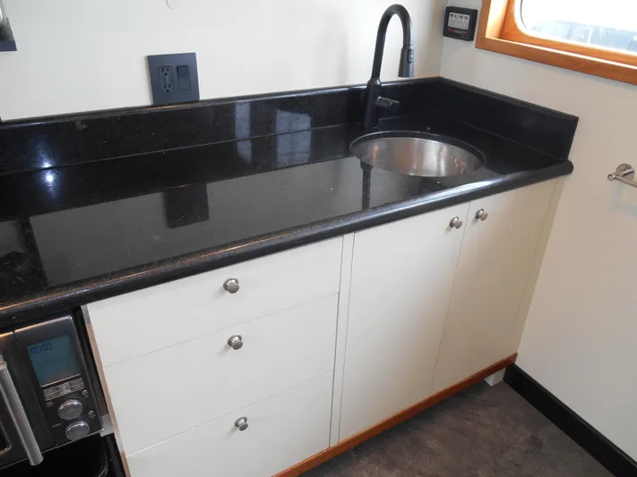 Suspense Yacht Photos Pics Kitchen area of a 2005 Inace Trawler with black countertop and sink.