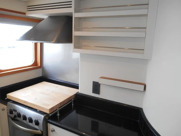 Suspense Yacht Photos Pics 2005 Inace Trawler kitchen with stove, cutting board, and sleek black countertops.